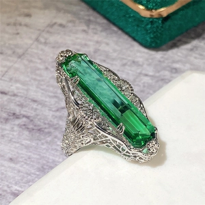 Détail d'une bague émeraude vintage avec pierre verte rectangulaire et motif en métal évidé