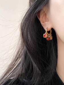 Detail of ethnic gold hoop earring with red zircon, beads, and vintage tassels on model