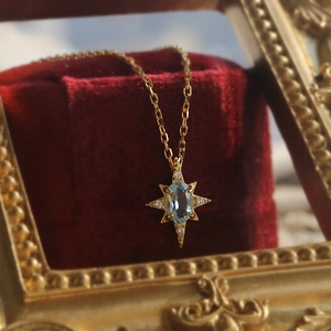 Detailed macro view of the gold starburst pendant with a light blue oval gemstone