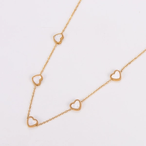Detailed macro view of five golden heart pendants with white mother of pearl inlay on necklace