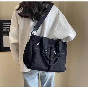 Detail of black corduroy crossbody bag with multiple utility pockets and adjustable strap