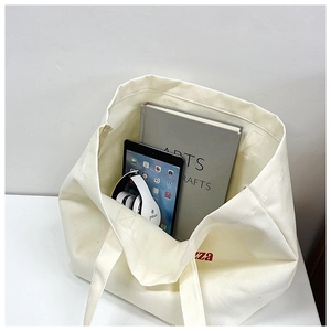 Top view of white large capacity canvas tote bag showing storage for books and tablets