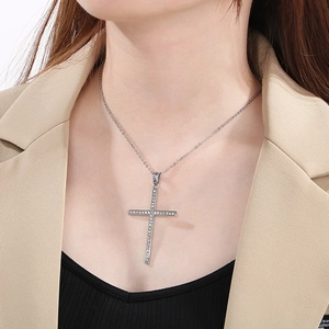 Close-up of a silver hip hop cross pendant encrusted with sparkling crystals on a model
