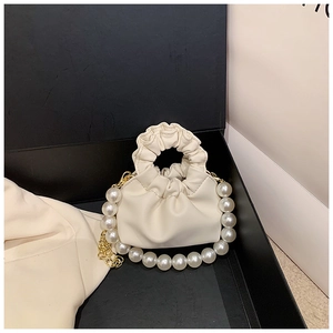 Detailed view of off-white ruched bucket bag with oversized pearl handle in black gift box