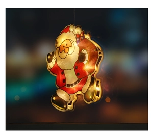 Detail of hanging Santa Claus LED light with warm glow against blurred city night background