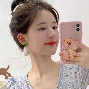 Selfie view of shell tassel earrings with green studs and white round shell pendants