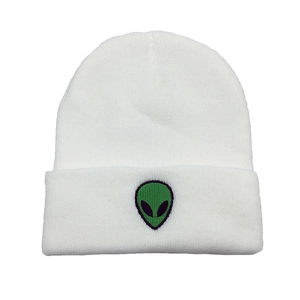 Close-up of green alien head embroidery on a white ribbed knit beanie for winter wear