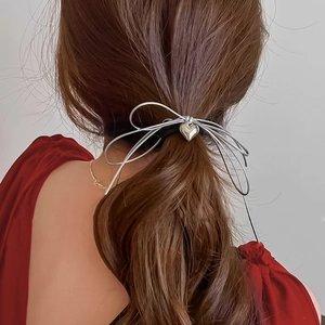 Detail of silver bow and heart pendant hair claw clip on model's ponytail