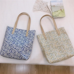 Detailed shot of floral canvas tote bags with leather straps and rivet reinforcement