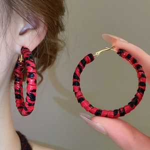 Détail de créoles à imprimé léopard rouge et noir avec fermoir en métal doré