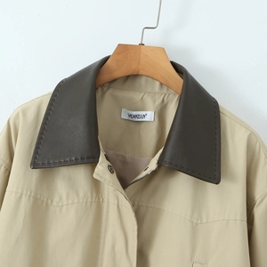 Vintage khaki trench coat with contrasting dark faux leather collar on a wooden hanger