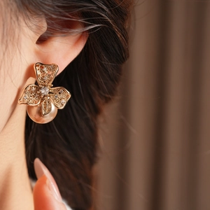 Gros plan sur une boucle d'oreille fleurie avec perle champagne et zircone sur le mannequin
