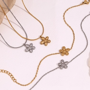 Flower pendant necklace and bracelet set in gold and silver finish on beige surface