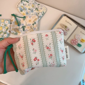 Close-up of floral cotton pouch with simple wish label and green woven zipper pull