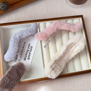 Plush faux fur hair clips set in grey pink beige and brown on white leather display