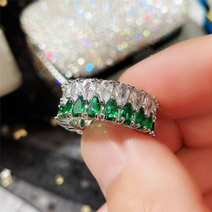 Macro d'une bague de luxe à double rangée avec pierres poires blanches et vert émeraude