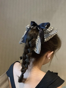 Détail d'un grand chouchou à carreaux avec ruban bleu marine sur une tresse élégante