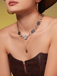 Detailed view of silver zircon necklaces and gold hoop earrings on a fashion model