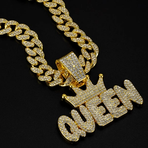 Close-up of golden iced-out QUEEN pendant with crown on Cuban link chain necklace