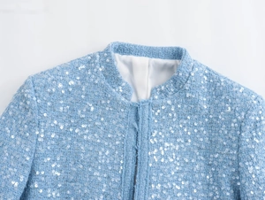 Detailed close-up of light blue tweed jacket with sparkling sequins and stand collar design