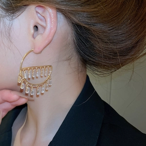 Macro view of gold hoop earrings featuring elegant rectangular zircon fringe pendants