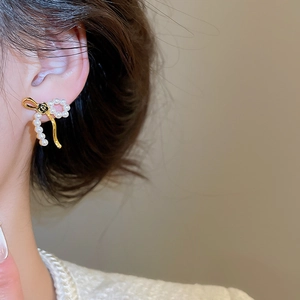 Macro detail of 18k gold plated bow earrings with white pearls and black camellia