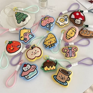 Flat lay of diverse plush bag charms with woven ropes and pearl chains on white desk
