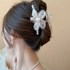 Detail of pink floral hair claw with sheer fabric petals and elegant pearl accents