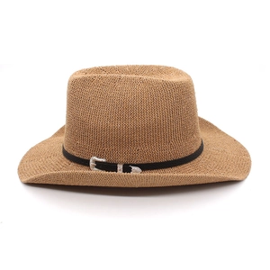 Détail d'un chapeau de cowboy en paille marron avec ruban noir et boucle argentée vintage