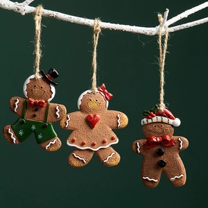 Three gingerbread man Christmas tree ornaments with festive hats and dresses on a white branch