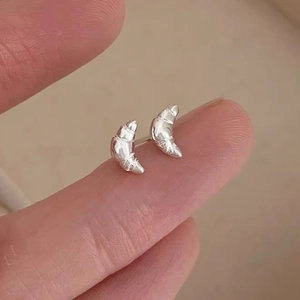 Pendientes de croissant en plata de ley 925 presentados sobre la punta del dedo