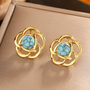 Detailed macro view of vintage flower stud earrings with turquoise stones in gold frames