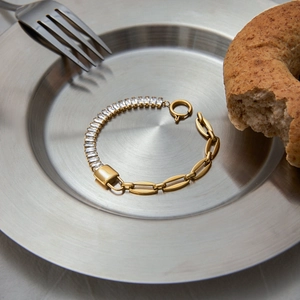 Detail view of heart-inspired gold bracelet with zircon stones on a metal tray