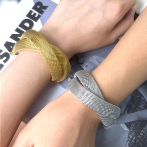 Detail view of woven mesh bracelets in gold and silver finish on female model wrists