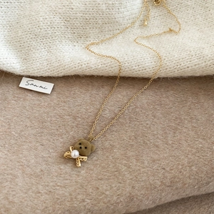 Detail view of a 18K gold-plated bear necklace with brown flocking and a small pearl accent