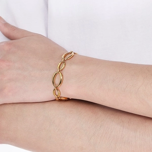 Detailed macro shot of a geometric gold stainless steel link bracelet worn on a female wrist
