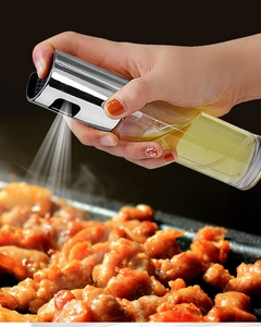 Detail of a glass oil sprayer with stainless steel nozzle spraying oil on grilled food