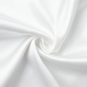 Détail du tissu en satin de soie blanc montrant une texture lisse et des plis drapés