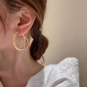 Minimalist double layer golden round hoop earrings worn by a model in a side profile view