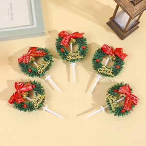 Five Christmas wreath cake toppers with red ribbons and green needles on beige background