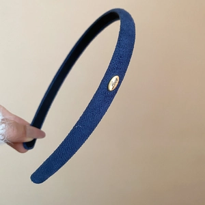 Détail d'un serre-tête bleu marine floqué avec une boucle dorée gravée 'Love' élégante