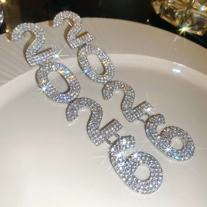 Close-up of sparkling rhinestone-studded 2026 earrings on a white plate