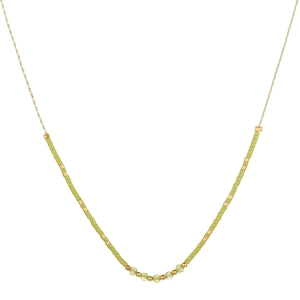 Gros plan sur collier doré minimaliste avec perles vertes et cristaux facettés