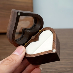 Macro shot of heart-shaped walnut ring box with white velvet lining and glass window