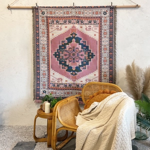 Detail of bohemian tapestry with ethnic geometric patterns and fringe on a white wall