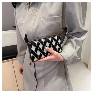 Detail of long zipper wallet with black and white woven pattern and golden hardware
