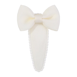 Detailed close-up of cream grosgrain bow hair clip with wavy edges and fabric texture