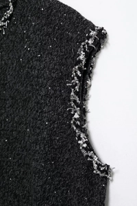 Détail du tissu en tweed noir avec paillettes et bordure tissée argentée d'une robe sans manches