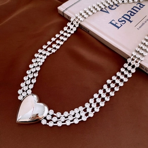 Detail of a triple-layer rhinestone body chain featuring a large polished silver heart pendant