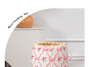 Close-up of quilted drawstring bag with pink rose patterns and soft cream fabric